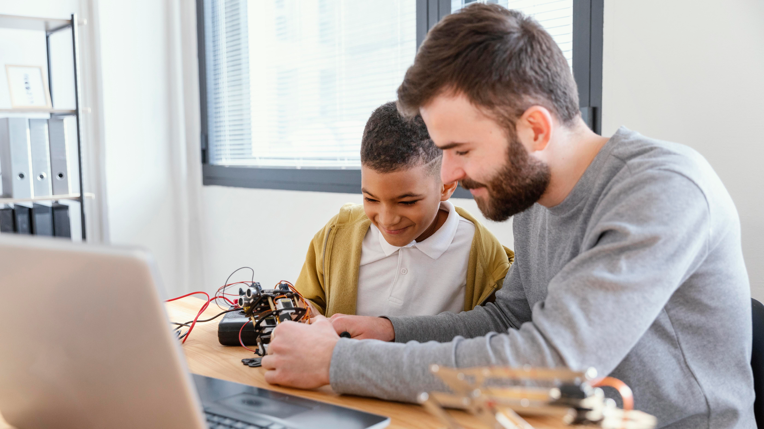 Student and teacher working on robotics with laptop open