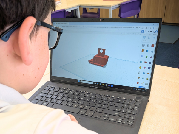A student working on a laptop using Tinkercad to design a 3D model in a classroom setting.