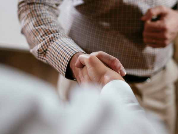 Two people shaking hands, shown in a close-up view, symbolising agreement, partnership, or a professional interaction.