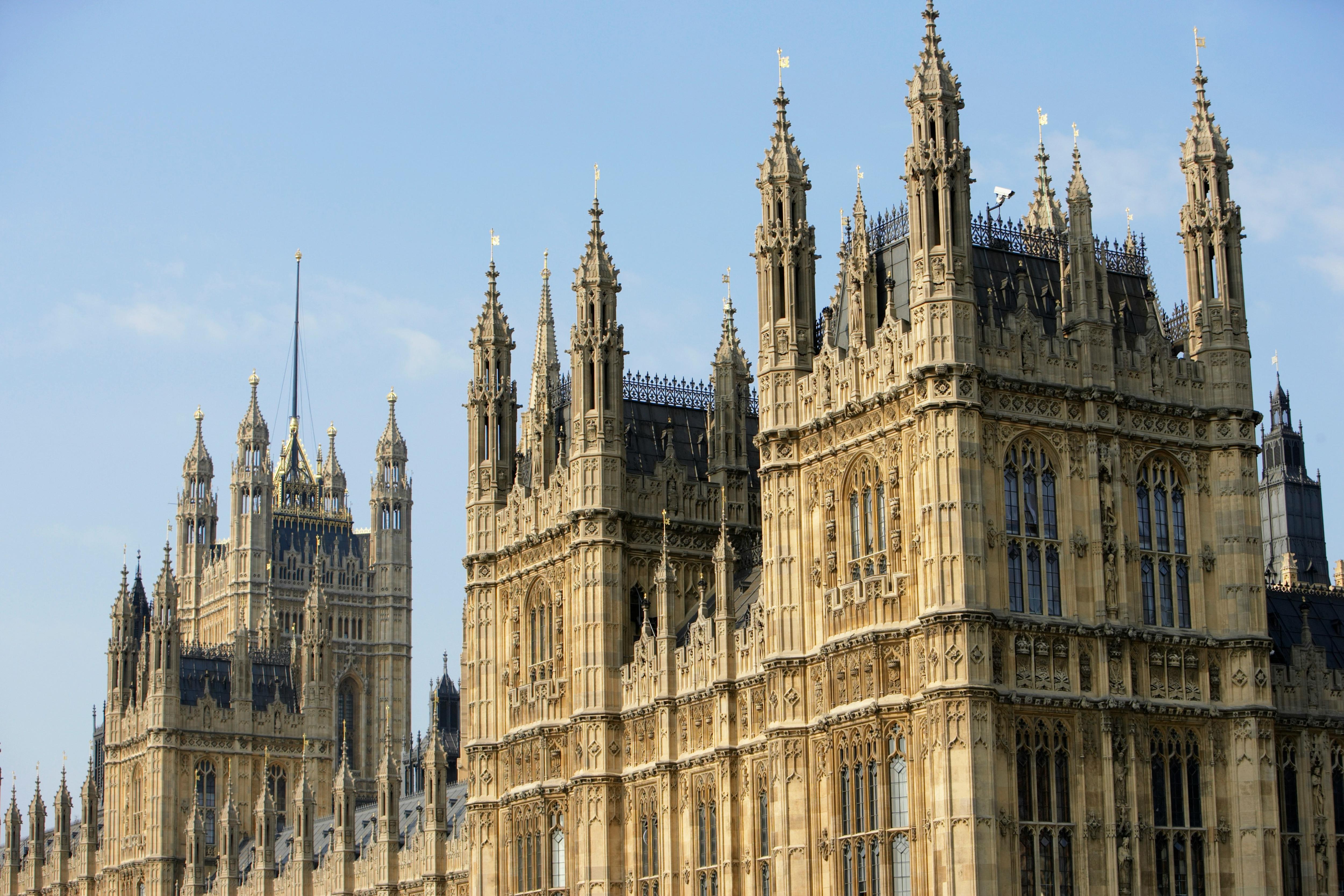 View of the UK Houses of Parliament in London under a clear blue sky.