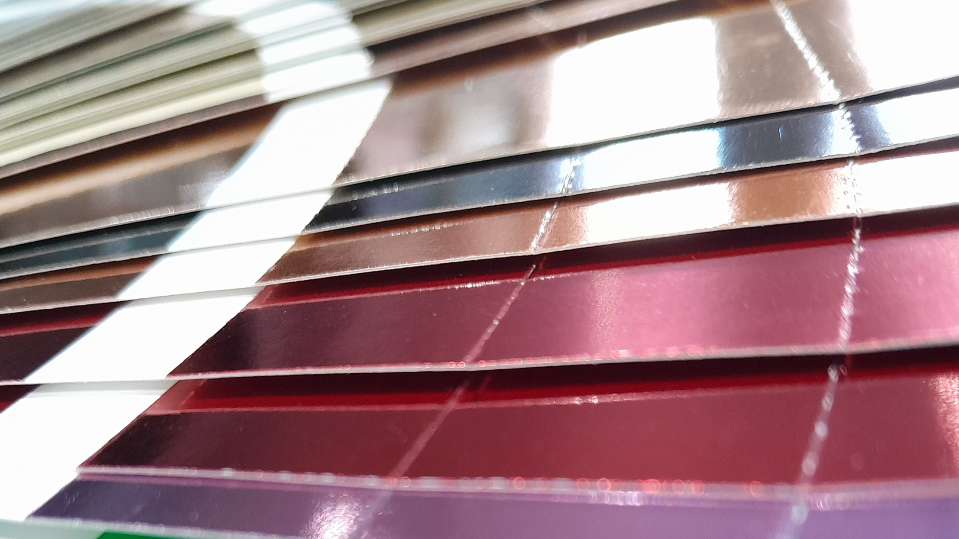 Close-up of stacked coloured plastic or acrylic sheets, showing layered edges, reflective surfaces, and different material colours used in manufacturing and product design.