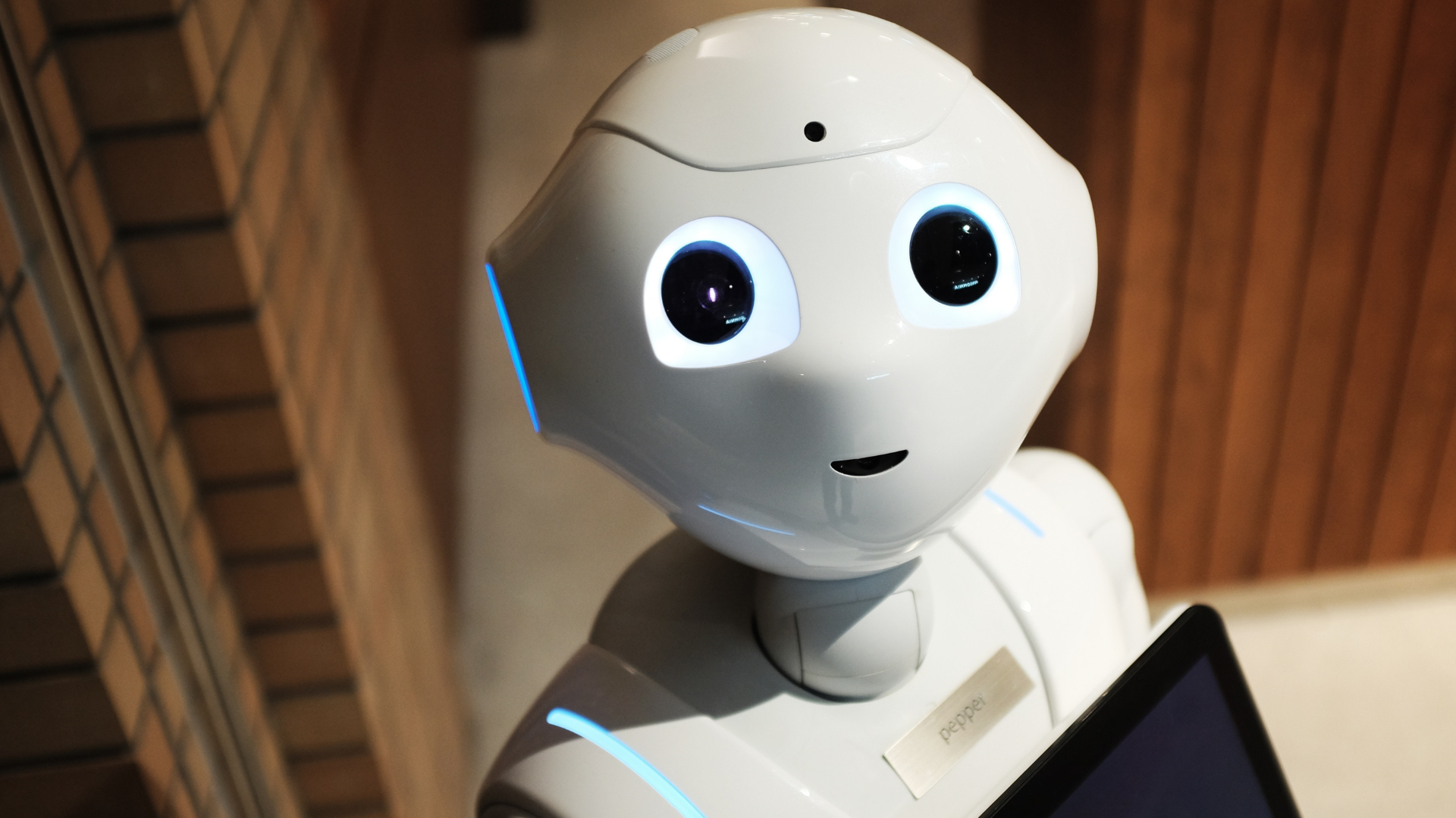 A humanoid service robot with illuminated eyes and a tablet interface, designed for human interaction.