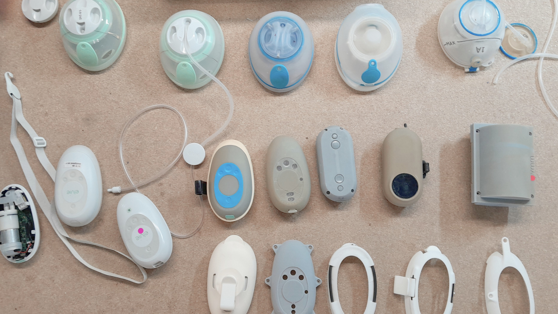 A collection of assistive medical and wearable device components arranged to show different casings, controls and internal parts.