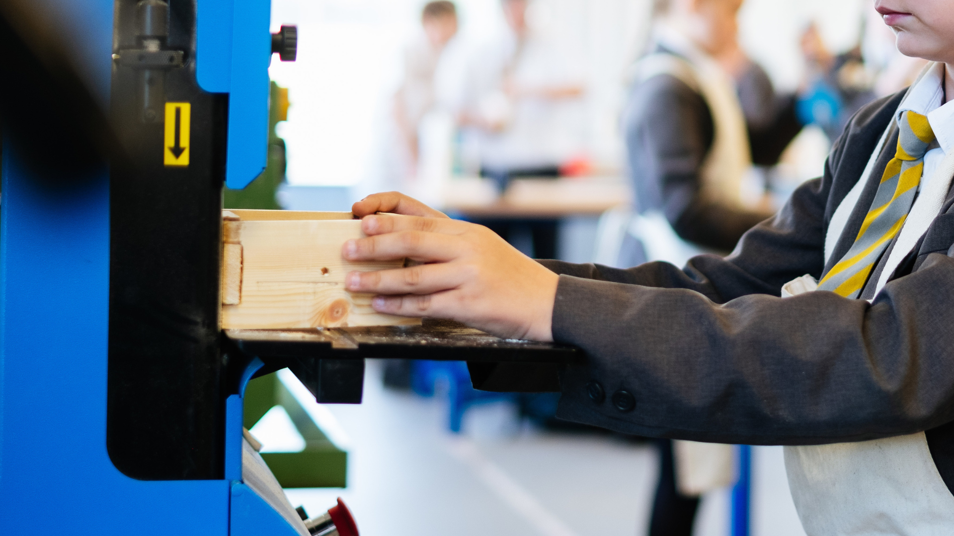 A secondary school student uses a machine to shape a piece of wood during a design and technology lesson.