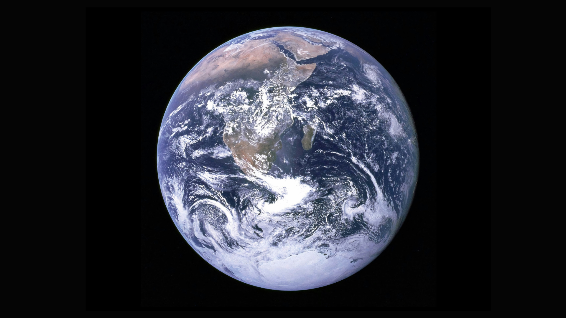 View of Earth from space showing continents, oceans and cloud patterns against a black background.
