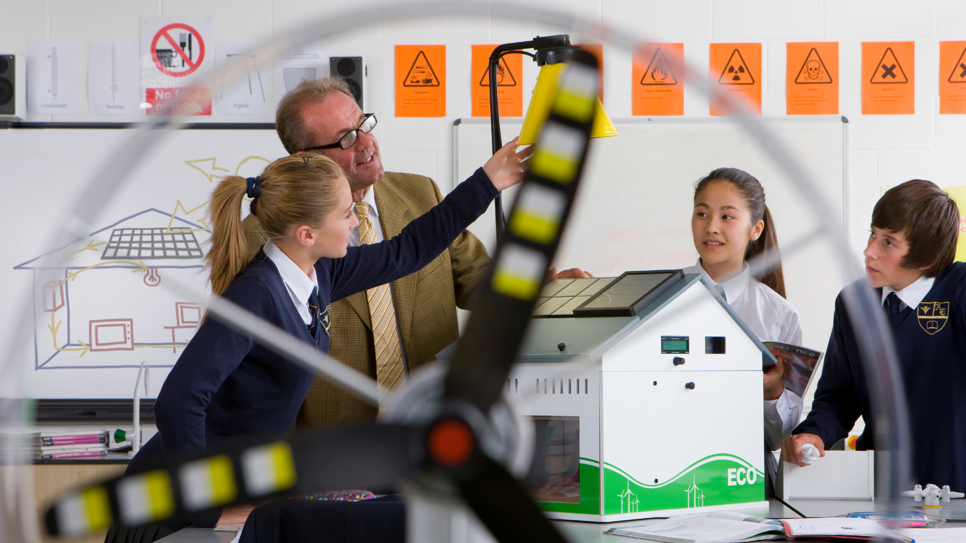 A Design and Technology teacher working with secondary school students as they explore a renewable energy model and prototype in a classroom setting.