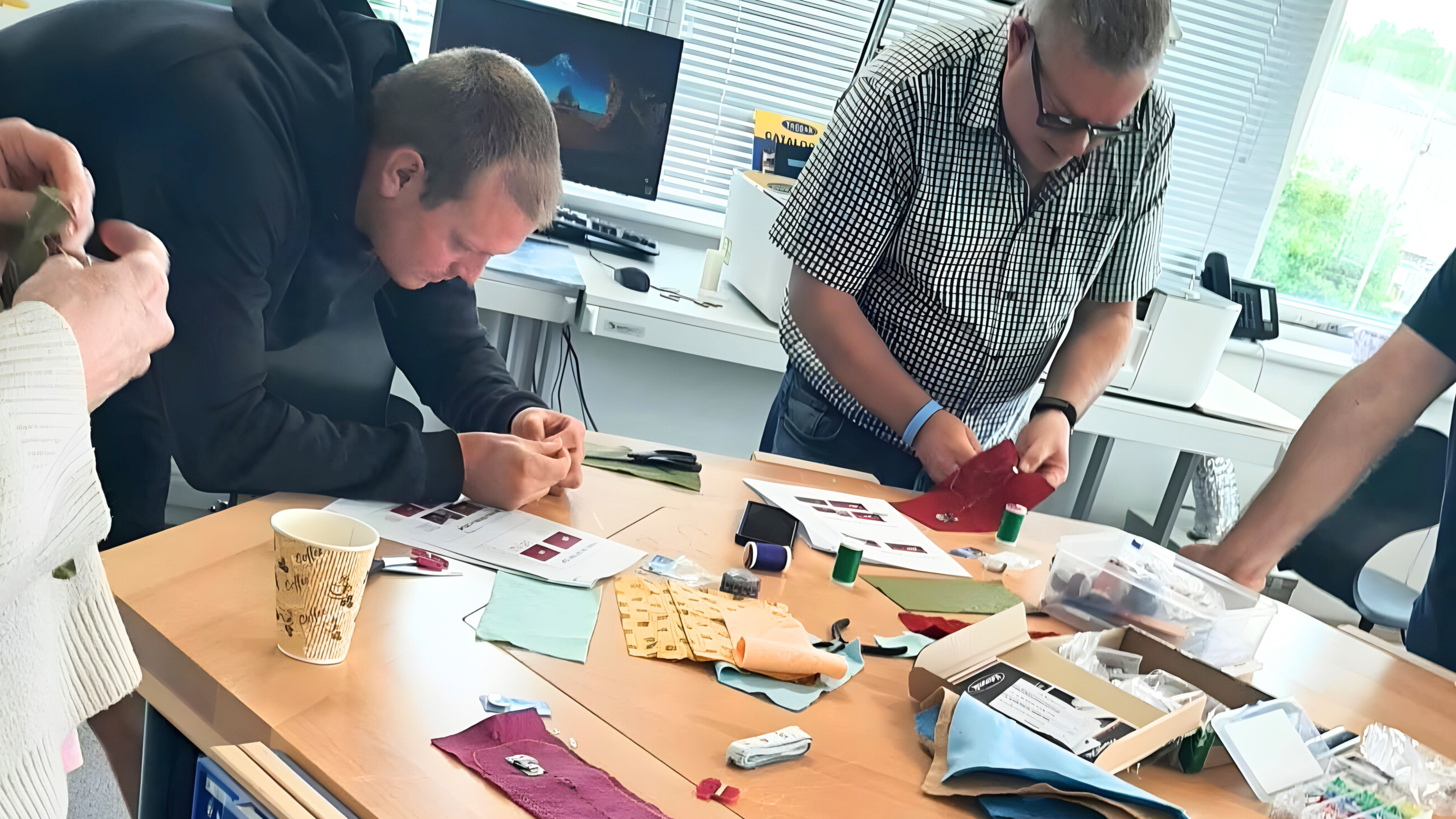 Teachers working together around a table, exploring textiles, materials and components during a hands-on design and technology session.