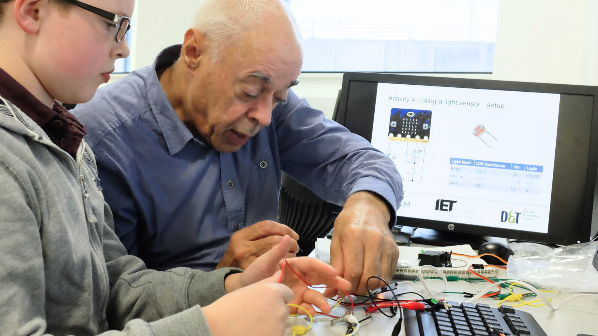 A teacher supporting a student as they work with electronics components and wiring during a design and technology lesson.