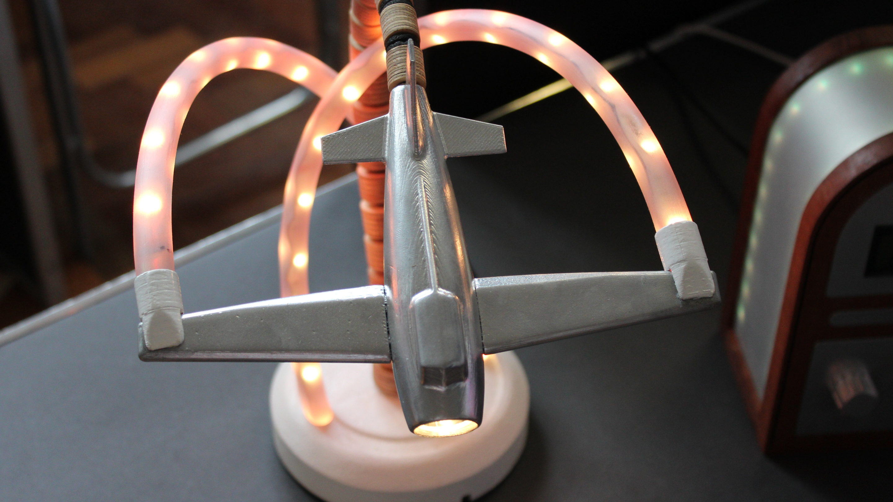 Close-up of a student-designed model aircraft lamp with integrated LED lighting, showcasing form, structure and electronic components.