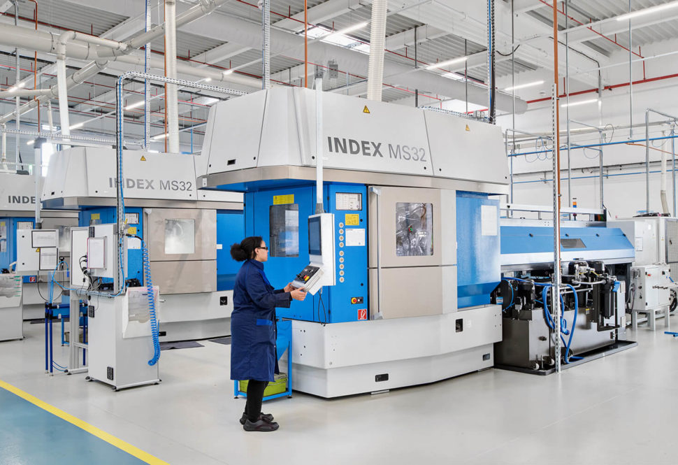 A technician operating an INDEX MS32 CNC machine on a factory floor, demonstrating automated precision manufacturing processes.