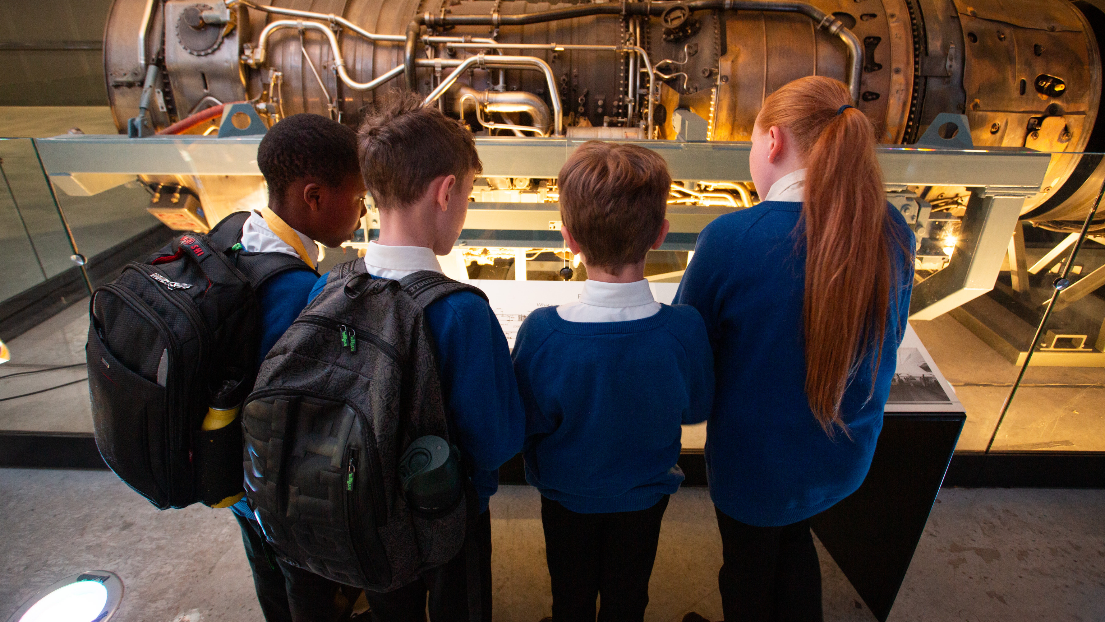 Group of school children looking at a plane engine