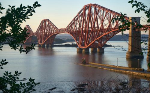 The image shows the Forth Bridge in Scotland, spanning a body of water.