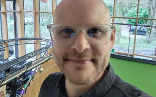 Portrait of a smiling man with glasses standing indoors near