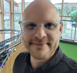 Portrait of a smiling man with glasses standing indoors near